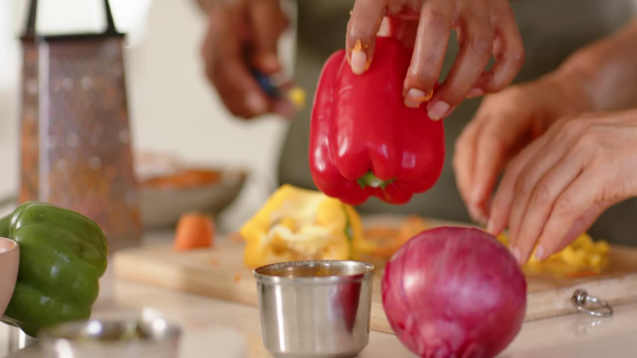 Amiche di diverse etnie che iniziano a preparare il pasto, tagliando i peperoni su un tagliere con una ciotola a coste