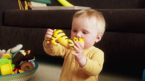 small blue-eyed toddler playing with a tiger toy on the ground pouting her lips