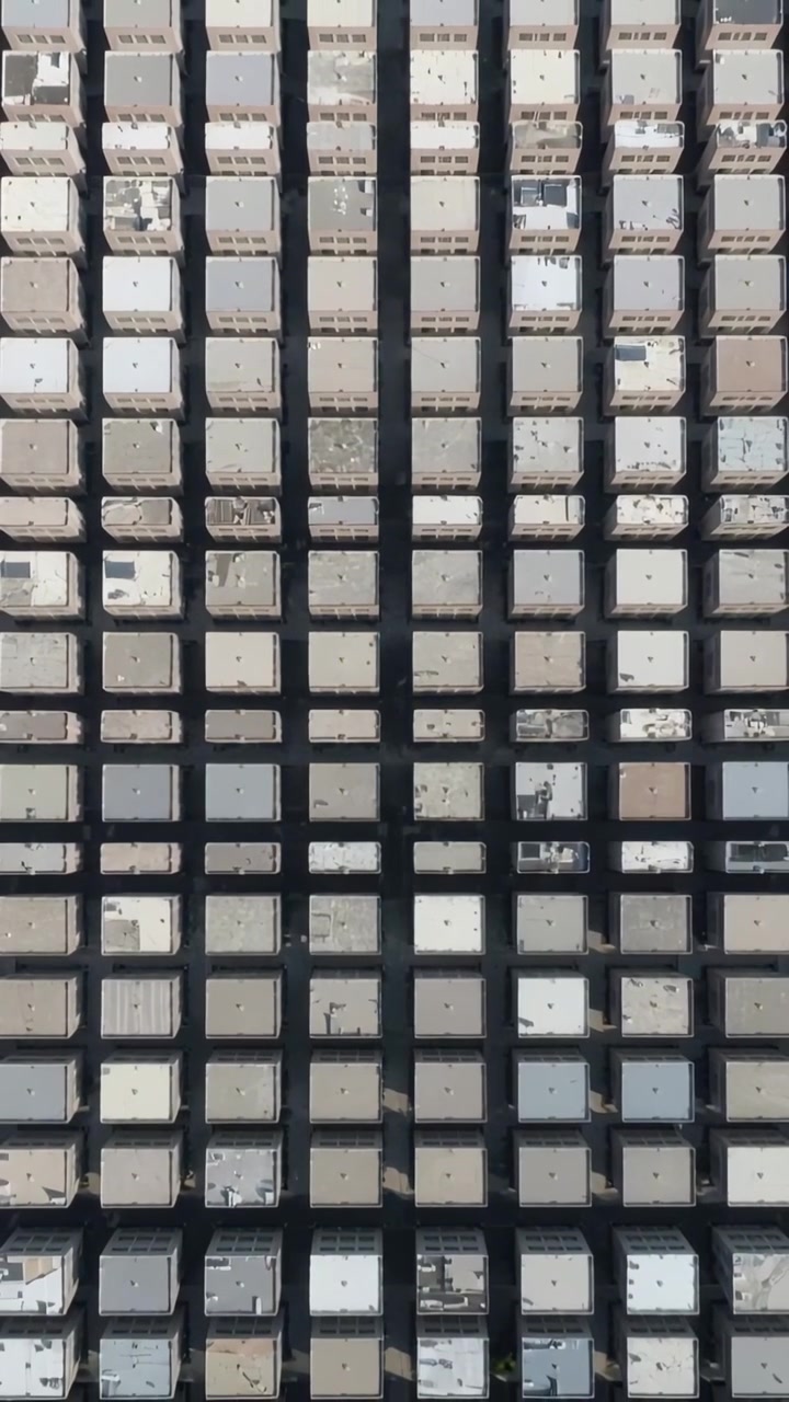 Video verticale: Telecamera aerea che si sposta catturando una griglia di tetti piatti, mostrando prese d'aria e strade.