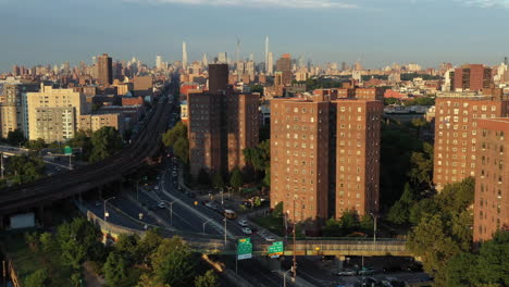 Cinematic-aerial-golden-hour-trucking-shot-showing-Harlem-Housing-Projects,-the-FDR-drive-highway-and-elevated-commuter-train-tracks-coming-from-Midtown-Manhattan