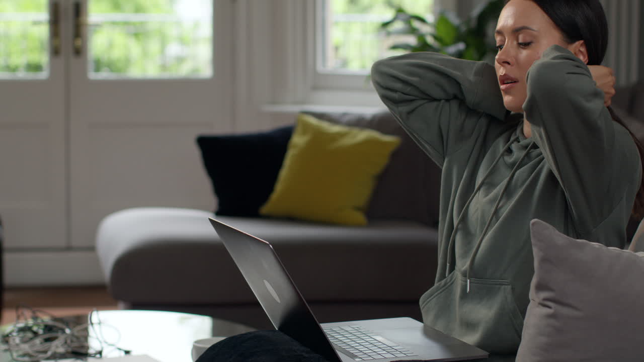 Anxious Woman Sitting Indoors On Sofa Working From Home Using Laptop Worried About Cost Of Living Crisis 2