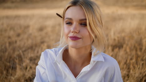 chica rubia poniendo spikelet en el peinado retrato. mujer romántica sentada en el campo