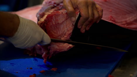 slow motion close up of a male chef slicing and cutting the skin off of a fresh blue fin tuna