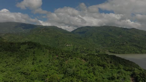 Drone-flying-over-lush-mountains-and-forest-surrounding-Presa-de-Valdesia-dam