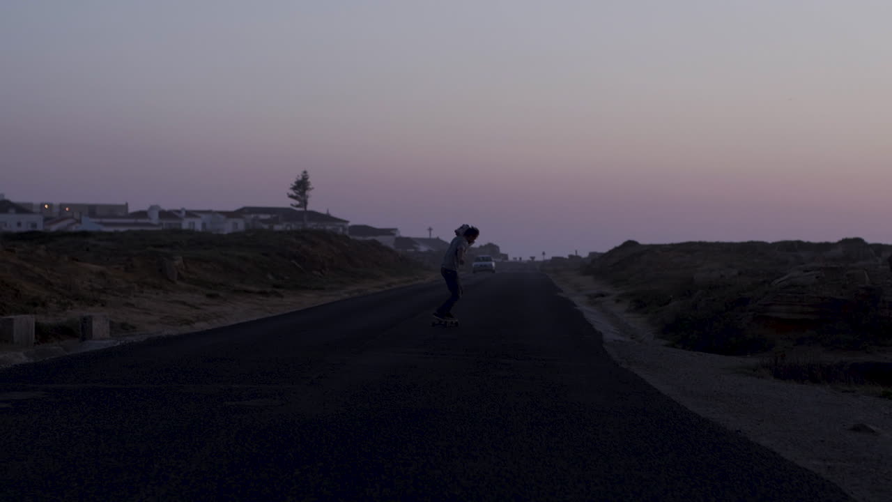 Skateboarder on a Coastal Road at Sunset