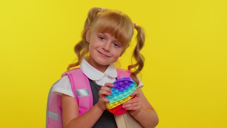 Joyful-pupil-girl-playing-with-pop-it-sensory-anti-stress-toy-kid-presses-on-squishy-bubbles-game