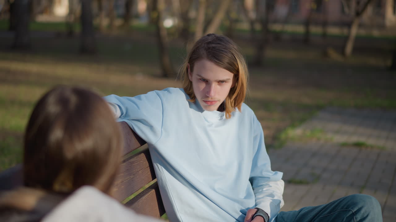 조용한 십 대가 야외에서 휴식을 취하고 있어요. 평화로운 공원 환경에서 햇볕이 좋은 오후 시간에 명상에 잠긴 젊은 남성이 벤치에 기대어 오후 햇살을 즐기고 있는 모습이에요.