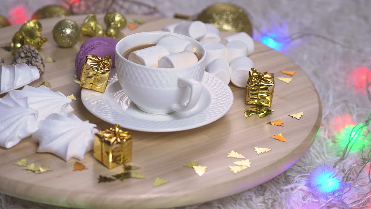fondo de navidad rotación de 360 grados. una taza de café con leche y marshmallows en salver de madera, otros dulces y decoraciones de navidad alrededor