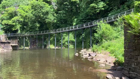 the millennium walkway in the town of new mills, united kingdom, showing the bridge, river and walkers in the distance