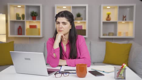 mujer trabajadora de oficina en casa mirando a la cámara deprimida.