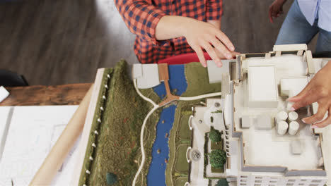 midsection of diverse male and female architects discussing architectural model, slow motion