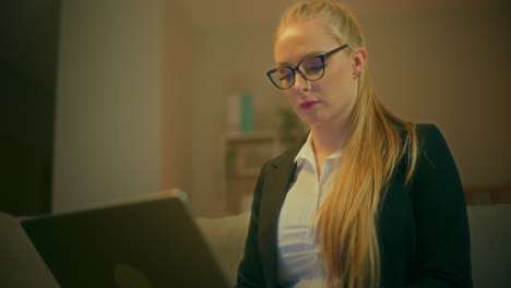 woman in suit works remotely on laptop late at night at home