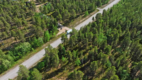 vista aérea rodeando una caravana que conduce por una carretera del bosque boreal, día de verano en laplandia