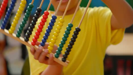 Mid-section-of-African-American-schoolboy-using-abacus-in-classroom-at-school-4k