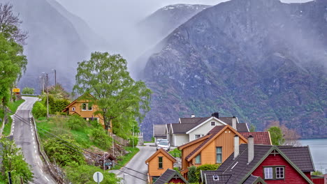 Wide-shot-of-fog-passing-over-scenic-mountainside-houses-with-winding-road