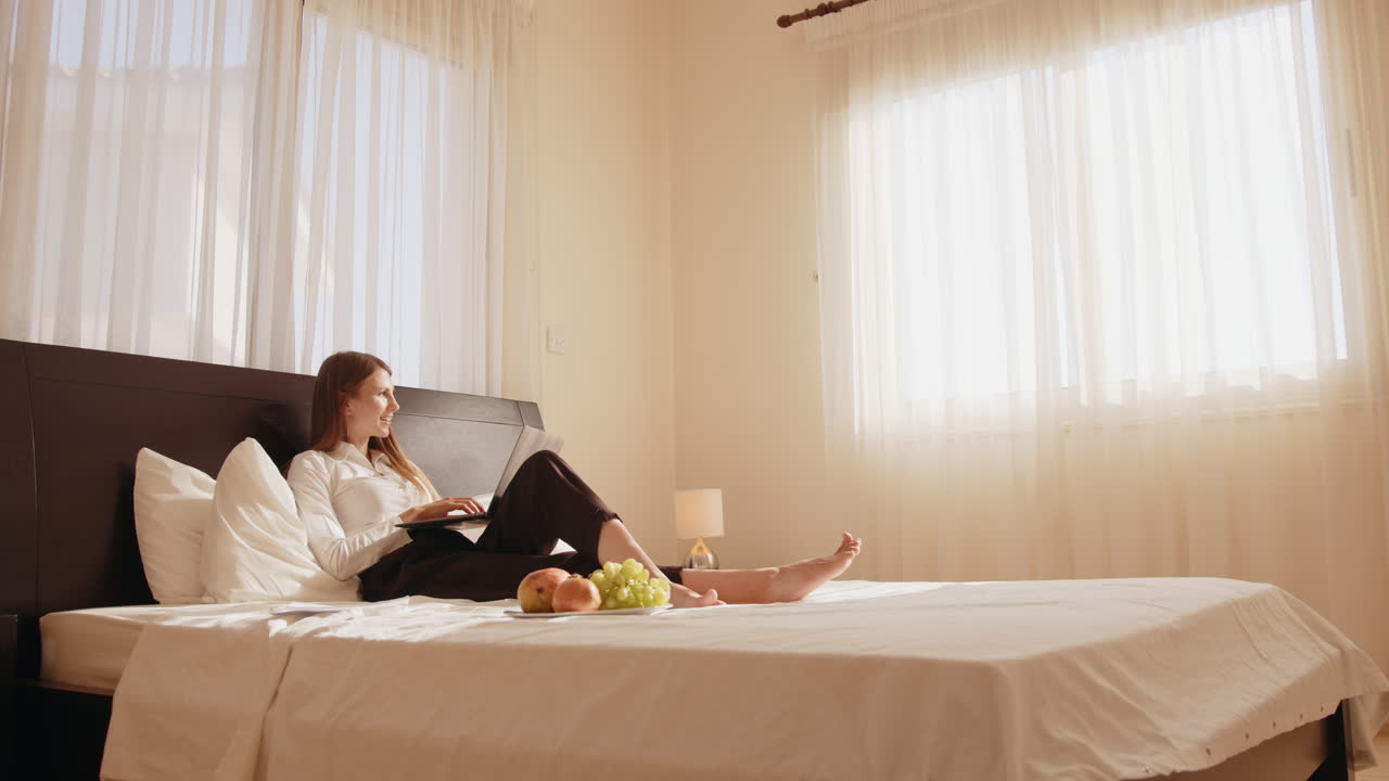 침대에서 노트북으로 일하는 여자