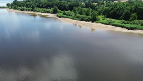 cinematic-drone-view-as-it-flies-over-a-big-blue-lake-and-takes-in-the-beach