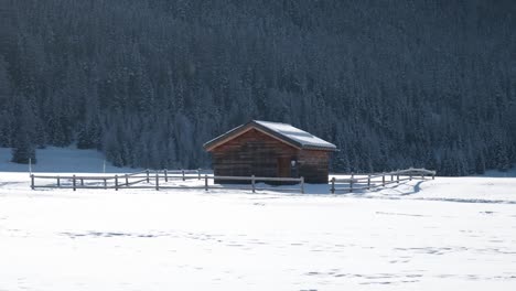 wooden cabin surrounded by sonwy covered winter landscape and trees is background