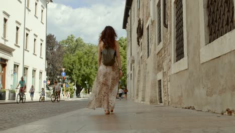 Female-tourist-in-beautiful-dress-explores-Verona,-rear-low-angle-view