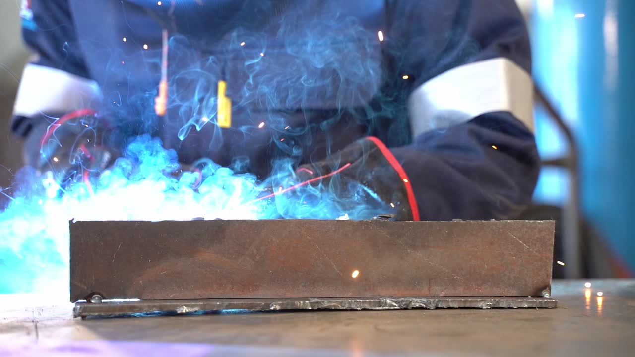 A slow motion gimbal shoot of a man welding two pieces of metal together