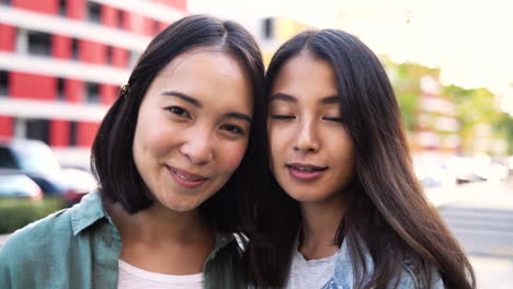 outdoor portrait of two beautiful young japanese girls looking and smiling at camera 2