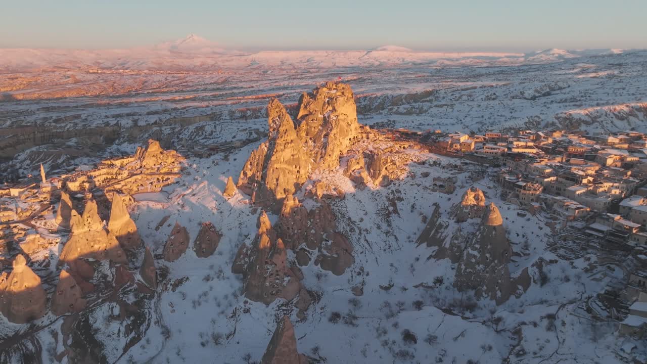 Top down Drone view over Uchisar castle Sunrise casts a warm glow over Cappadocia's snow-covered rock formations, Turkey, Turkiye