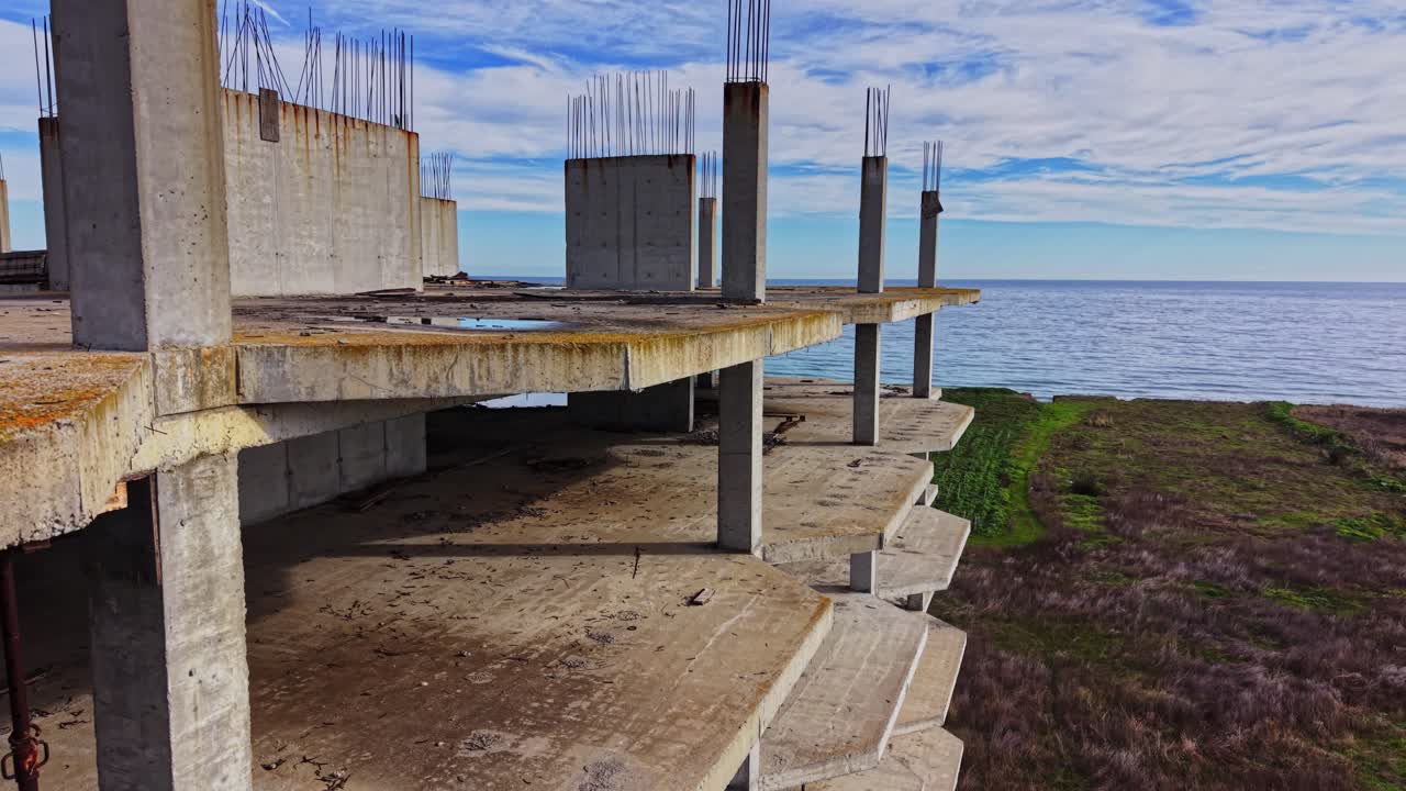 Coastal construction site with abandoned structure and green fields