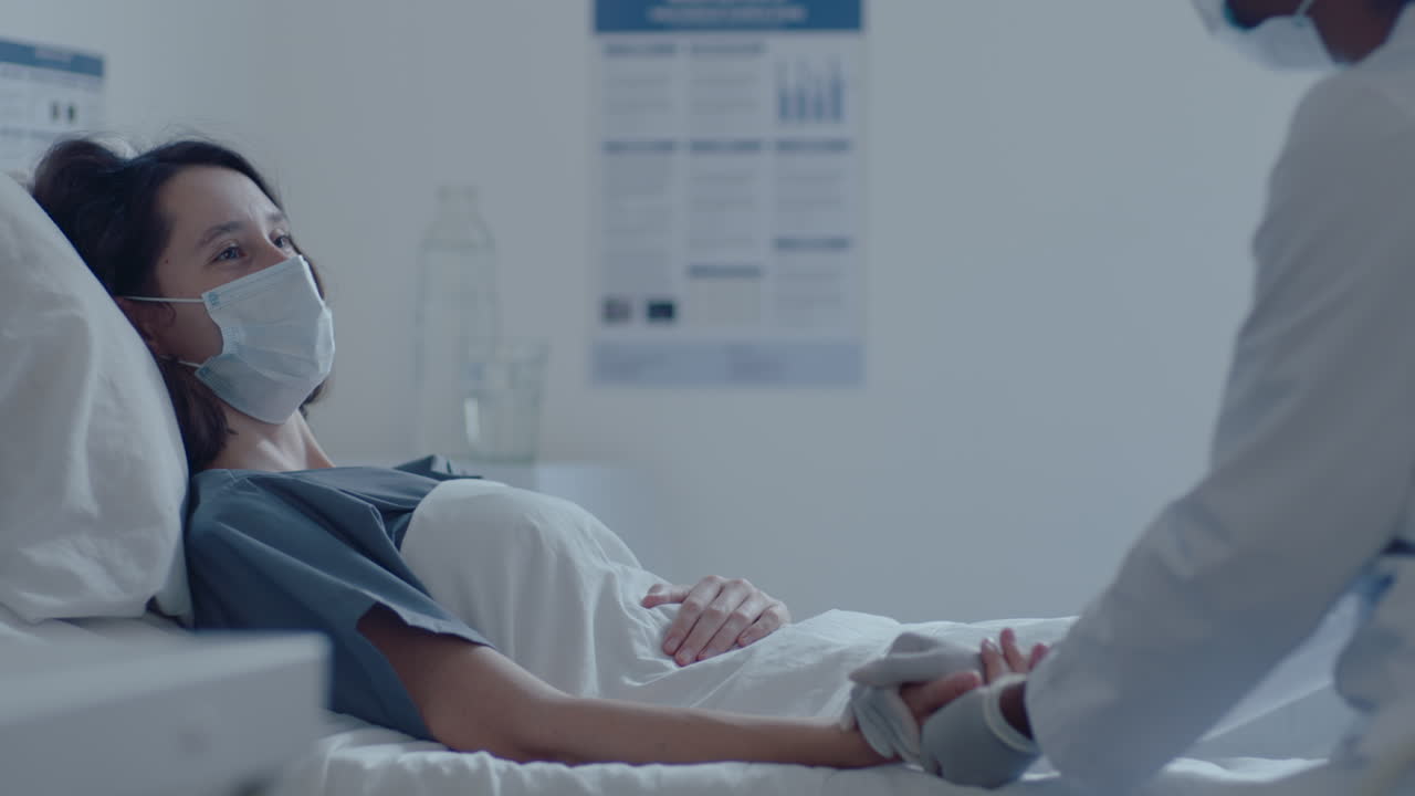 Empathic Doctor in Mask Supporting Sick Woman in Hospital Ward