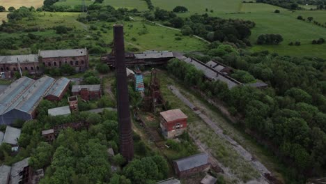 abandoned old overgrown coal mine industrial museum buildings aerial view rising above chimney