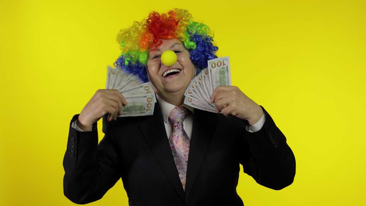 Anziana imprenditrice clown, libera professionista e capo, che balla con banconote in contanti.