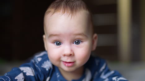 face of an adorable toddler boy looking curiously into camera. little baby smiling and saliva dripping from his mouth.