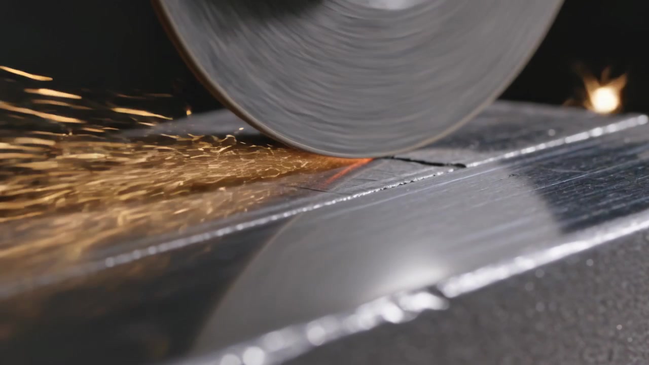 Bajando una rueda abrasiva para esmerilar una barra de metal en un banco de taller y hacer una incisión, creando chispas.