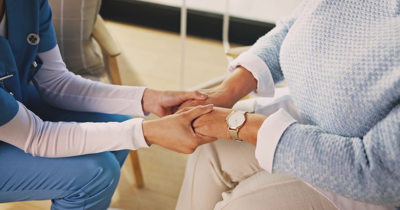 Nurse Comforting Elderly Patient by Holding Hands