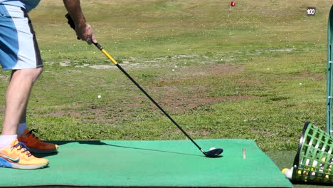 hombre practicando el swing de golf en el campo de manejo