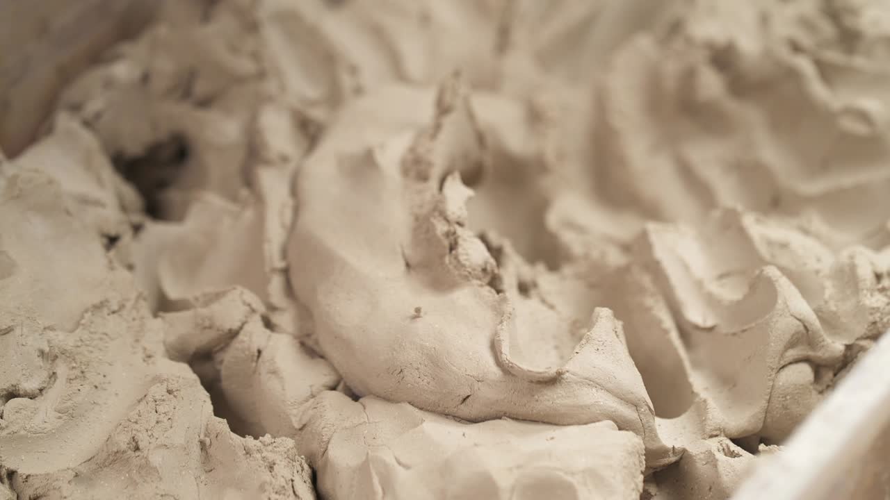 A close-up of male sculptors hands taking and shaping clay for creating ceramic statue in professional workshop