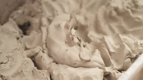 a close-up of male sculptors hands taking and shaping clay for creating ceramic statue in professional workshop