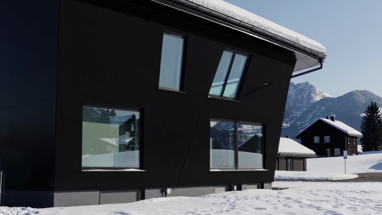 Exterior of a contemporary black house with snow covered surroundings and a mountain range reflected in its windows. Creating a striking contrast between modern architecture and the natural landscape