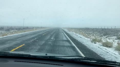 pov driving into snow storm on paved highway through empty grasslands, eastern oregon