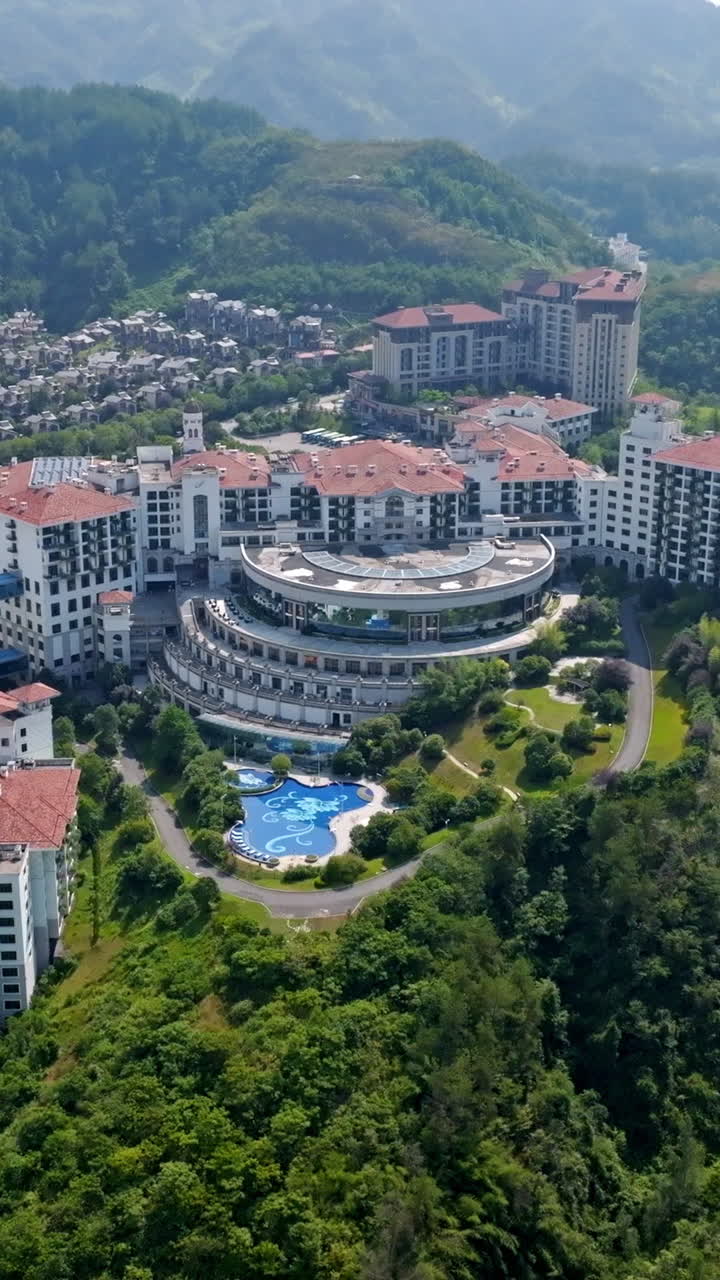 Portrait drone shot of in front of a huge hotel complex, summer day in China