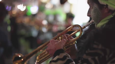 disguised manm with make up playing trumpet on carnival festival, in focus