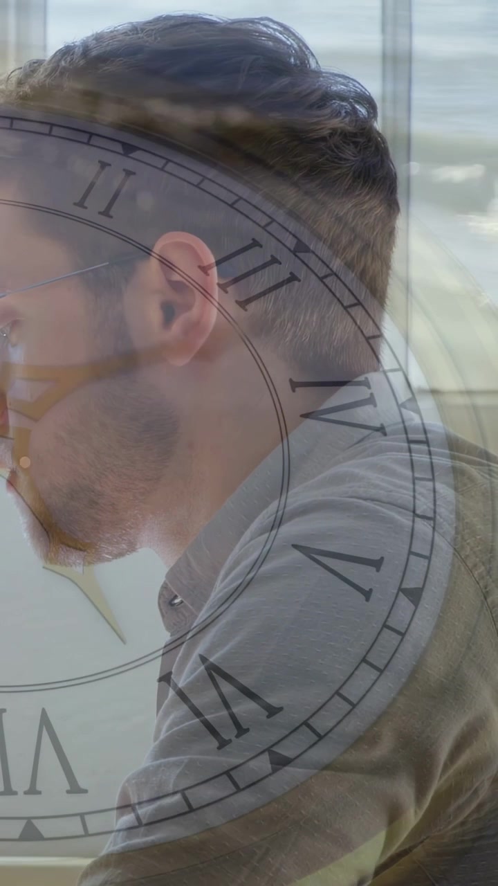 Video verticale: Uomo seduto alla scrivania vicino alla finestra, affari, sovrapposizione di un orologio che segna il tempo, che cattura l'attenzione.