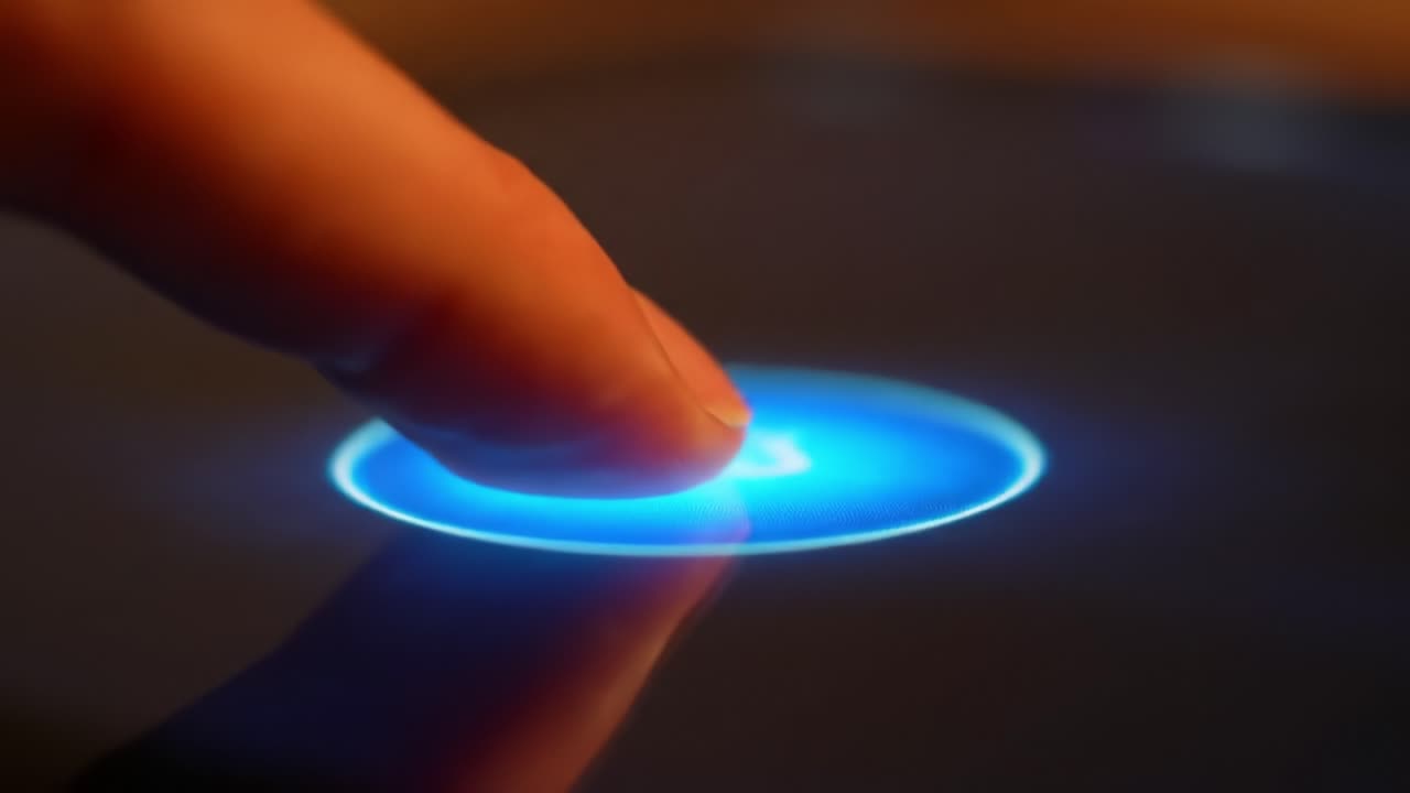 A close-up of a finger gently pressing a luminous button on a sleek surface, showcasing modern technology and user interaction at a tech event.