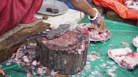 un primer plano de una mujer cortando y pesando peces en una balanza