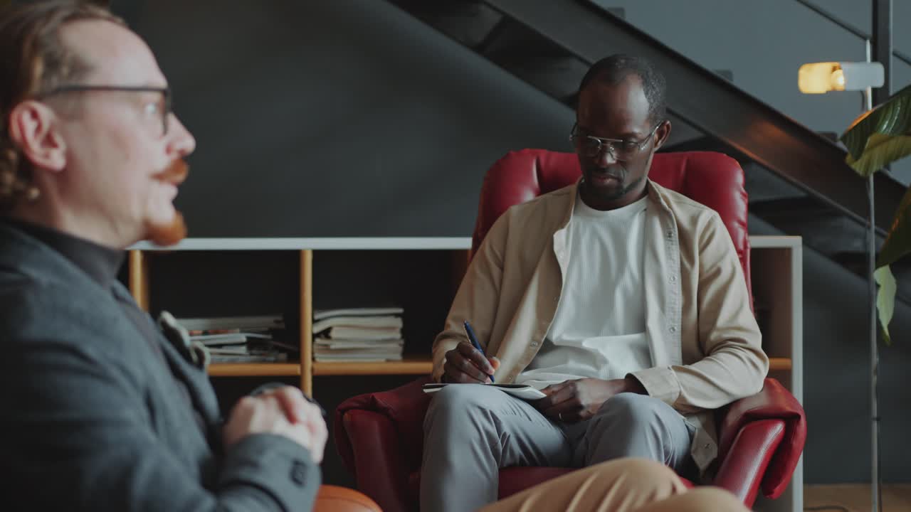 Man Talking Openly to Psychologist Taking Notes during Therapy Session