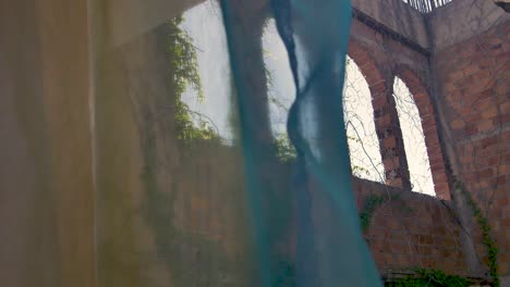 a slow motion focus pull shot looking through coloured curtains in a greek apartment out onto interesting stone archways