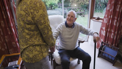 elderly man receiving assistance from caregiver at home