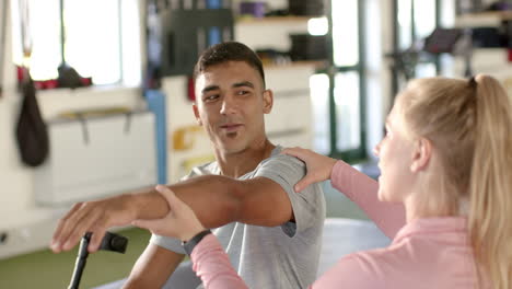 man in disability rehab exercising arm with assistance from female therapist