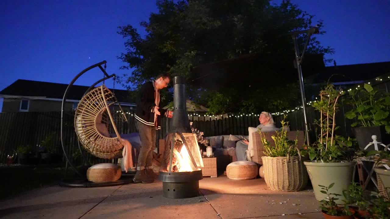 Backyard nighttime ambiance, potted plants, garden furniture, fire pit