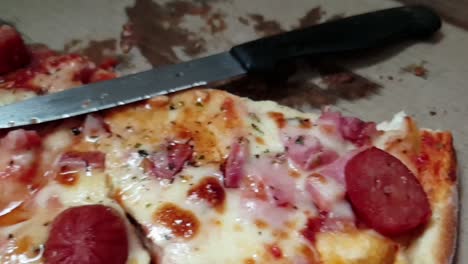 pizza perfecta, queso cheddar extra fundido, salami extra y aderezos de pepperoni servidos calientes, rebanados con un cuchillo de sierra de acero inoxidable