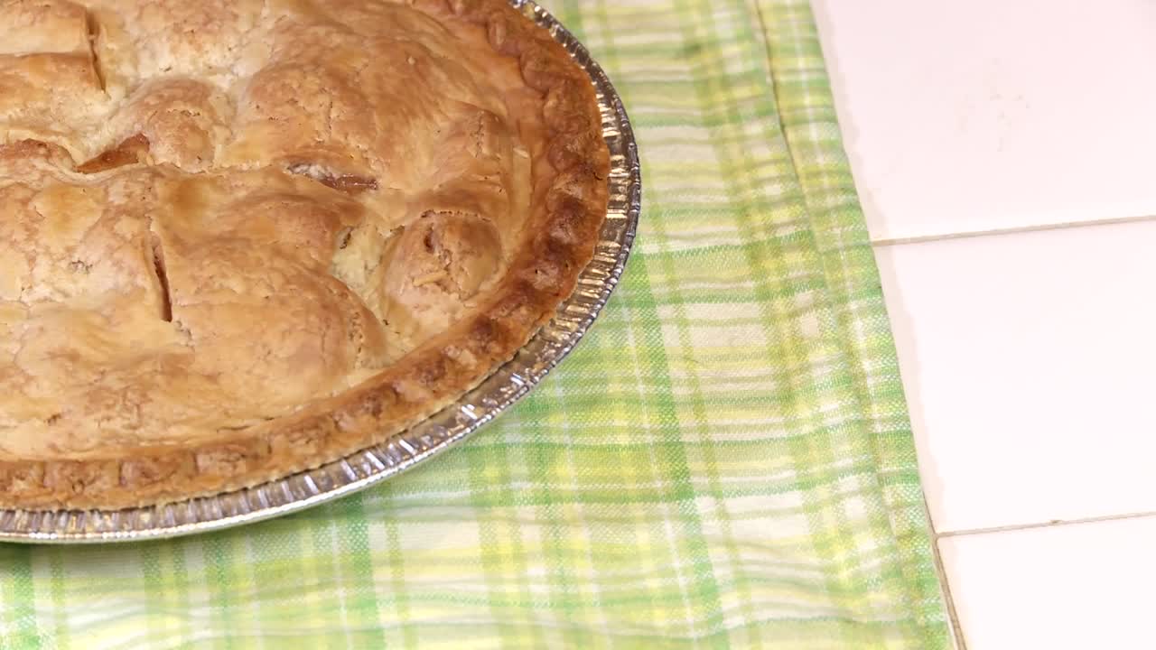 una tarta de manzana recién horneada se enfría en una toalla de cocina verde